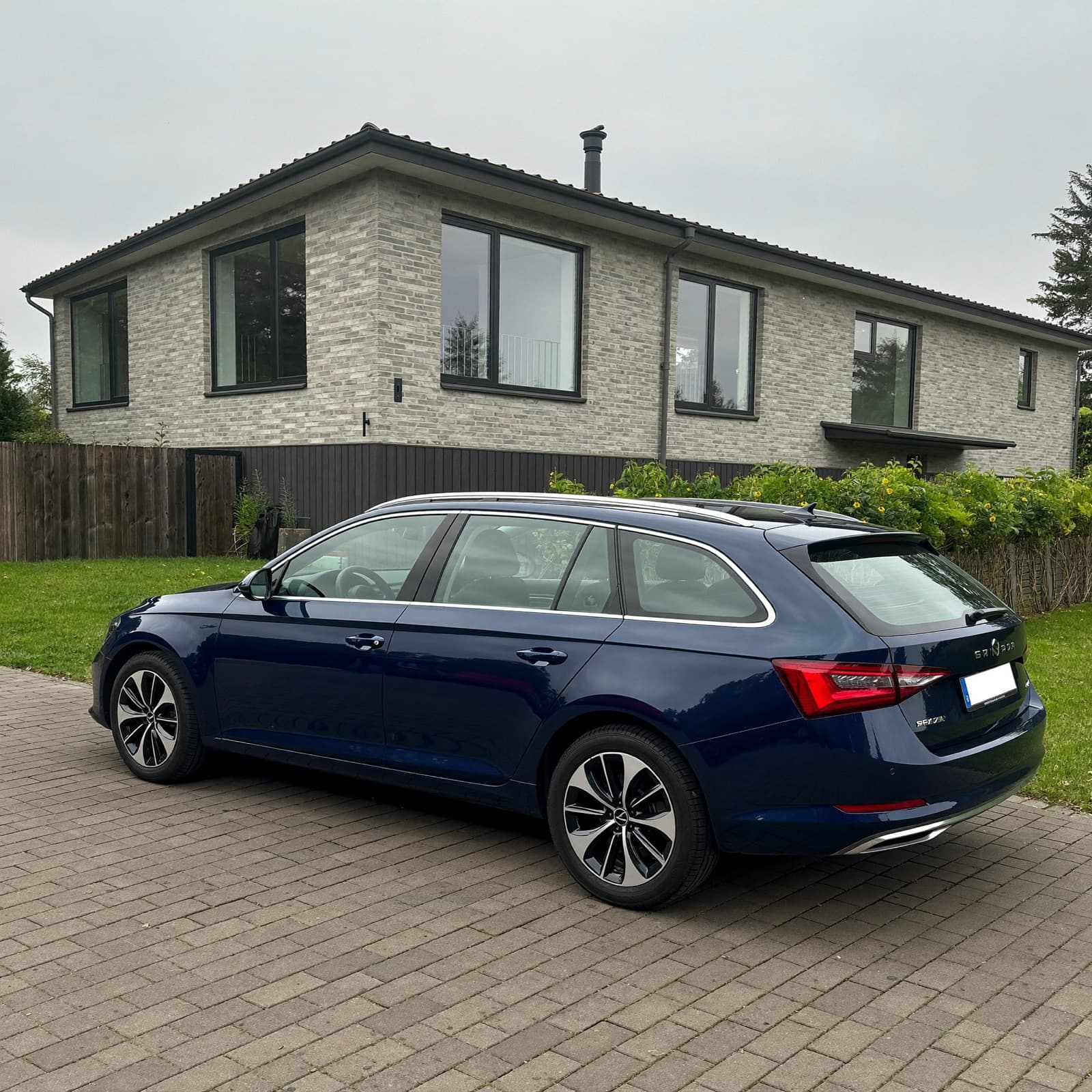Mørkeblå stationcar parkeret i en dansk indkørsel